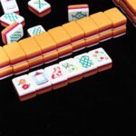 American Mahjong tile faces and orange layered backs on a dark background